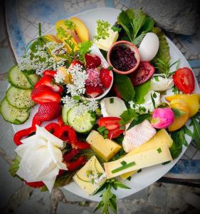 a plate full of different types of cheese and vegetables at Eulennest - Tiny House im Habichtswald in Schauenburg +16 photos