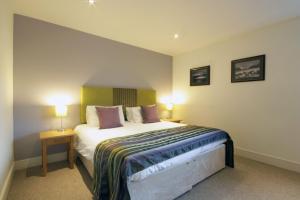 a bedroom with a large bed with two lamps at By The Bridge Apartments in Inverness