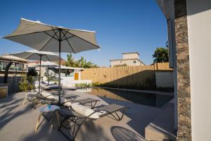 a group of chairs and an umbrella next to a pool at Moonlit Villa in Planos