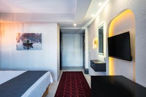a hotel room with a bed and a flat screen tv at Çınar Butik Hotel in Kaş