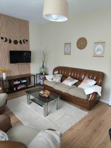 a living room with a leather couch and a table at Casa las granxias in El Escobal