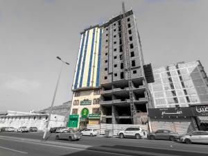 a tall building with cars parked in front of it at فندق مهوى الفؤاد 1 ذاخر توصيل مجاني للحرم Mahwa Alfoad 1 Hotel free bus to Haram in Mecca