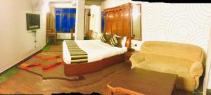 a bedroom with a bed and a couch and a chair at Hotel Mount View in Shimla