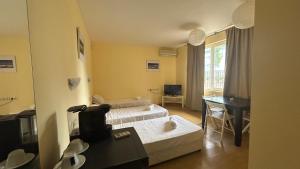 a hotel room with two beds and a desk at Корал in Obzor