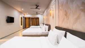 a hotel room with two beds and a flat screen tv at Hotel Pinaki Inn in Ujjain