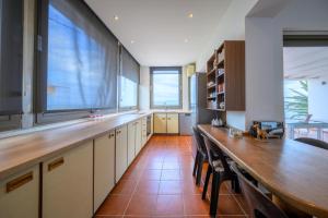 a large kitchen with a long table and some windows at Horizon House - Beachfront Escape in Nerántza