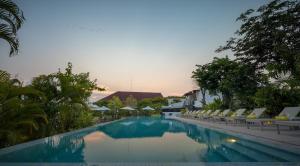 a swimming pool with lounge chairs and a resort at The Aviary Hotel in Siem Reap