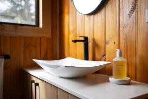 a bathroom with a sink and a bottle of soap at Rivendell Cottage - Off Grid cabin in Jackeys Marsh +8 photos