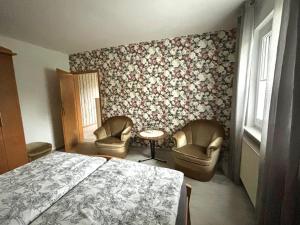 a bedroom with a bed and two chairs at Ferienwohnung Schöne Aussicht in Nieheim