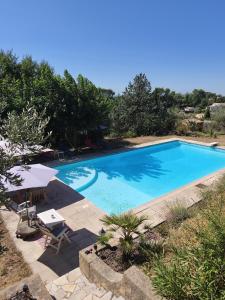 a large blue swimming pool with a table and chairs at Chambres d'hôtes de charme La Joséline in Flayosc