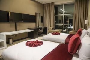 a hotel room with two beds and a flat screen tv at Basra Platinum Hotel in Al Başrah