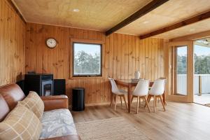 a living room with a couch and a table and chairs at Rivendell Cottage - Off Grid cabin in Jackeys Marsh