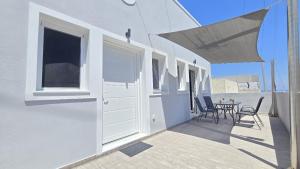 a white house with a patio with chairs and a table at Santorini Pictures apartment in Emporio