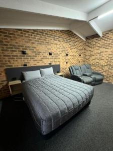 a bedroom with a bed and a couch and a chair at Clock Tower Motor Inn in Coonabarabran +22 photos