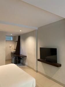 a bedroom with a bed and a tv on a wall at White Rock Lodge in Nusa Dua