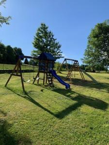 two playground equipment in a grassy field at Appartement dans maison à Corbelin proche Walibi in Corbelin