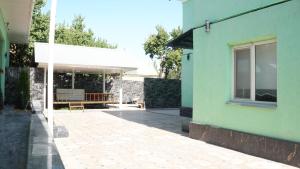 a green house with a patio and a building at Royal Pool Cottage in Shymkent
