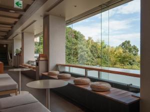 a room with a large window with a table and chairs at Soratoniwa Atami Izusan in Atami