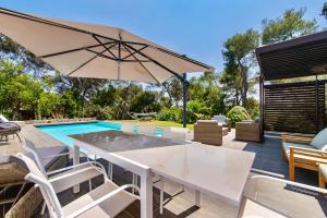 a patio with a table and umbrella and a swimming pool at villa d'engance et ses dépendances in Nîmes +22 photos