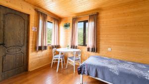 a bedroom with a bed and a table and windows at Ushguli Cabins l Cafe in Ushguli