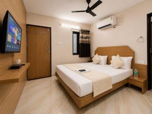 a bedroom with a bed and a flat screen tv at Hotel RR Palace in Rajkot