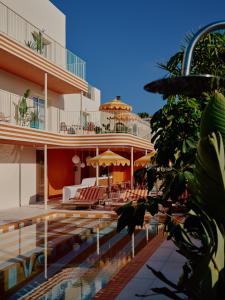 a resort with a swimming pool with chairs and umbrellas at Riviera Hotel Menorca in Ciutadella +32 photos
