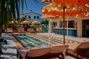 a pool with chairs and umbrellas next to a house at Riviera Hotel Menorca in Ciutadella