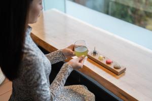 a woman holding a glass of wine and a tray of sushi at Soratoniwa Atami Izusan in Atami