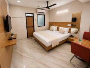a hotel room with a bed and a television at Hotel RR Palace in Rajkot +7 photos