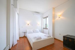 a bedroom with a white bed and a window at Horizon House - Beachfront Escape in Nerántza