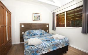 a bedroom with a bed with blue and white sheets and a window at Seaside Retreat in Mitchells Island +42 photos