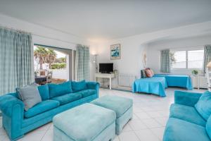 a living room with blue couches and a tv at Prainha Lounge in Alvor
