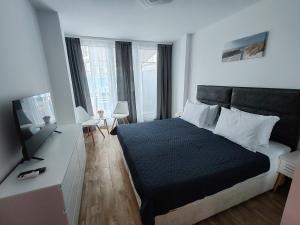 a bedroom with a large bed and a television at Kabakum Apartments in Golden Sands