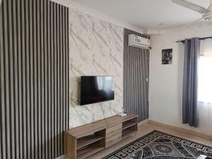 a living room with a television on a marble wall at Diani family friendly in Diani Beach