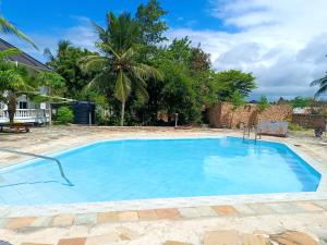 a large swimming pool with blue water at Diani family friendly in Diani Beach