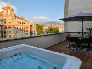 a bath tub on a balcony with a table and an umbrella at RYAP Puerta Real in Granada