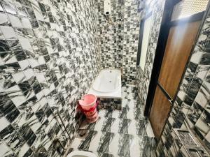 a tiled bathroom with a toilet and a sink at Hotel RR Palace in Rajkot