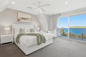 a bedroom with a white bed and a large window at Bayview Luxe Retreat in Tascott