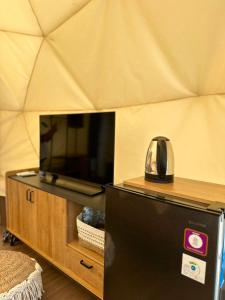 a black refrigerator in a room with a tv at Glamping Grand Mazaya Private Pool in Bandung