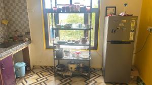 a kitchen with a refrigerator and a shelf with pots and pans at Kolaveri Homes in Bīr +8 photos