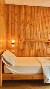 a bed in a room with wooden walls at Chalet Costa Rotian in Commezzadura