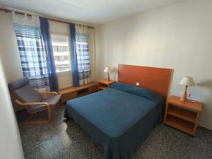 a bedroom with a bed and a chair and windows at Apartaments Lamoga - Boabi in Torredembarra