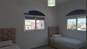 a room with two windows and a bed and a couch at Sidi Kankouch Bay in Tangier