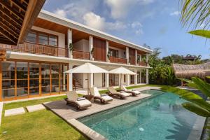 a villa with a swimming pool and lounge chairs at Villa Pura Bali in Canggu