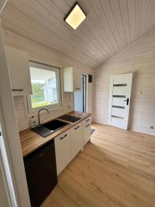 a kitchen with white cabinets and a sink and a window at Domki GAMA in Gąski