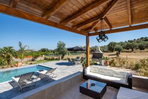 an outdoor patio with a swimming pool and a wooden pergola at George's Paradise in Afantou