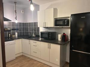 a kitchen with white cabinets and a black refrigerator at Le cocon du télésiège - Piscine chauffée - Métabief in Métabief