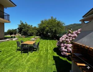 a table and chairs in a yard with pink flowers at Apartamento La Hojarada 20809 in Argoños