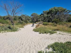 a person riding a motorcycle on a sandy road at Barnard Beach House in Broadwater