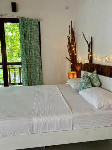 a bedroom with a white bed with a window at Papaya Hikkaduwa in Hikkaduwa